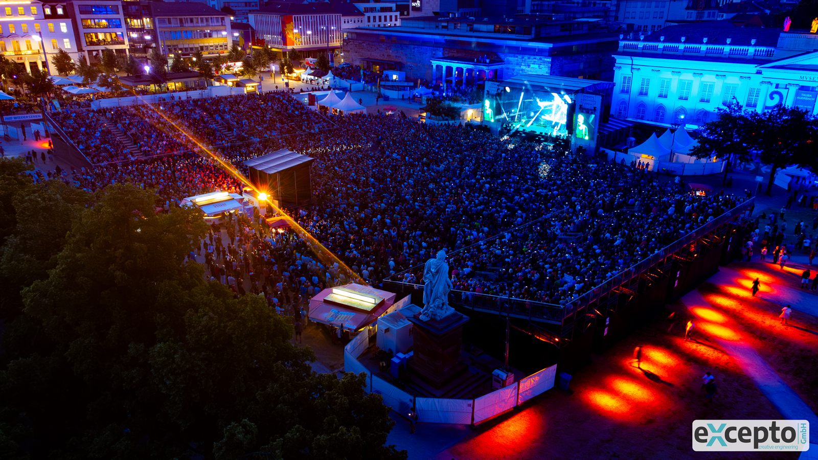 Open-Air-Konzert auf einem Stadtplatz aus der Luft, Bühne, Publikum und Absperrungen